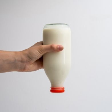 A red Milk Topz cap stops milk leaking from a bottle being held upside down